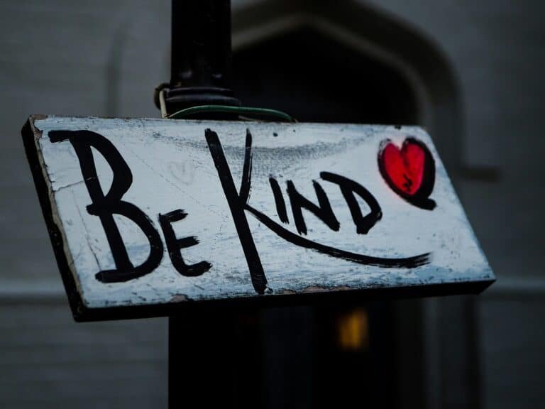 Panneau en bois vieilli avec l'inscription 'Be Kind' accompagnée d'un cœur rouge dessiné, symbolisant la gentillesse et la bienveillance. Photo inspirante sur la bonté et l'humanité, idéale pour illustrer des articles sur la solidarité et les bonnes actions.