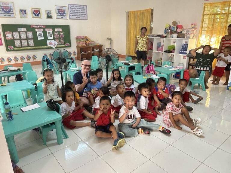 Luigi entouré d’enfants philippins dans une salle de classe rénovée à Limbauan, grâce à un projet pour cofinancer une salle de classe aux Philippines.