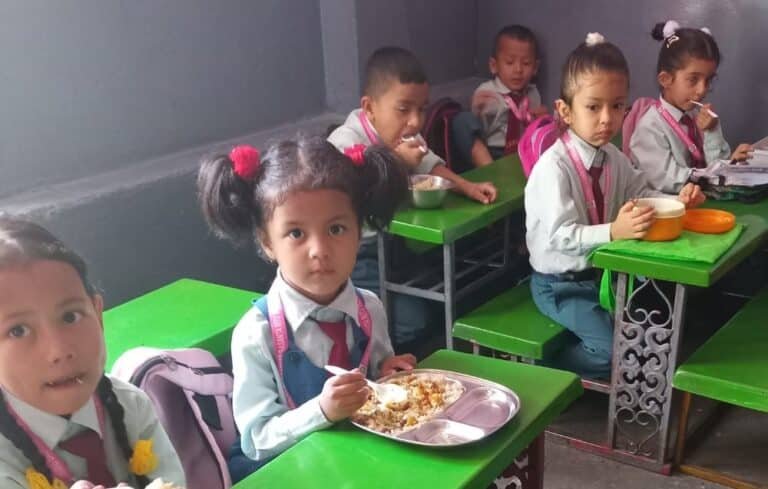 Notizie protette dal Nepal - Aswini e i suoi compagni in uniforme scolastica consumano il pranzo a scuola in Nepal